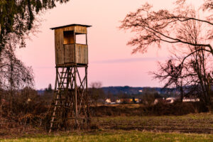 Hunting tower after sunset in rural scenery against pink sky.
